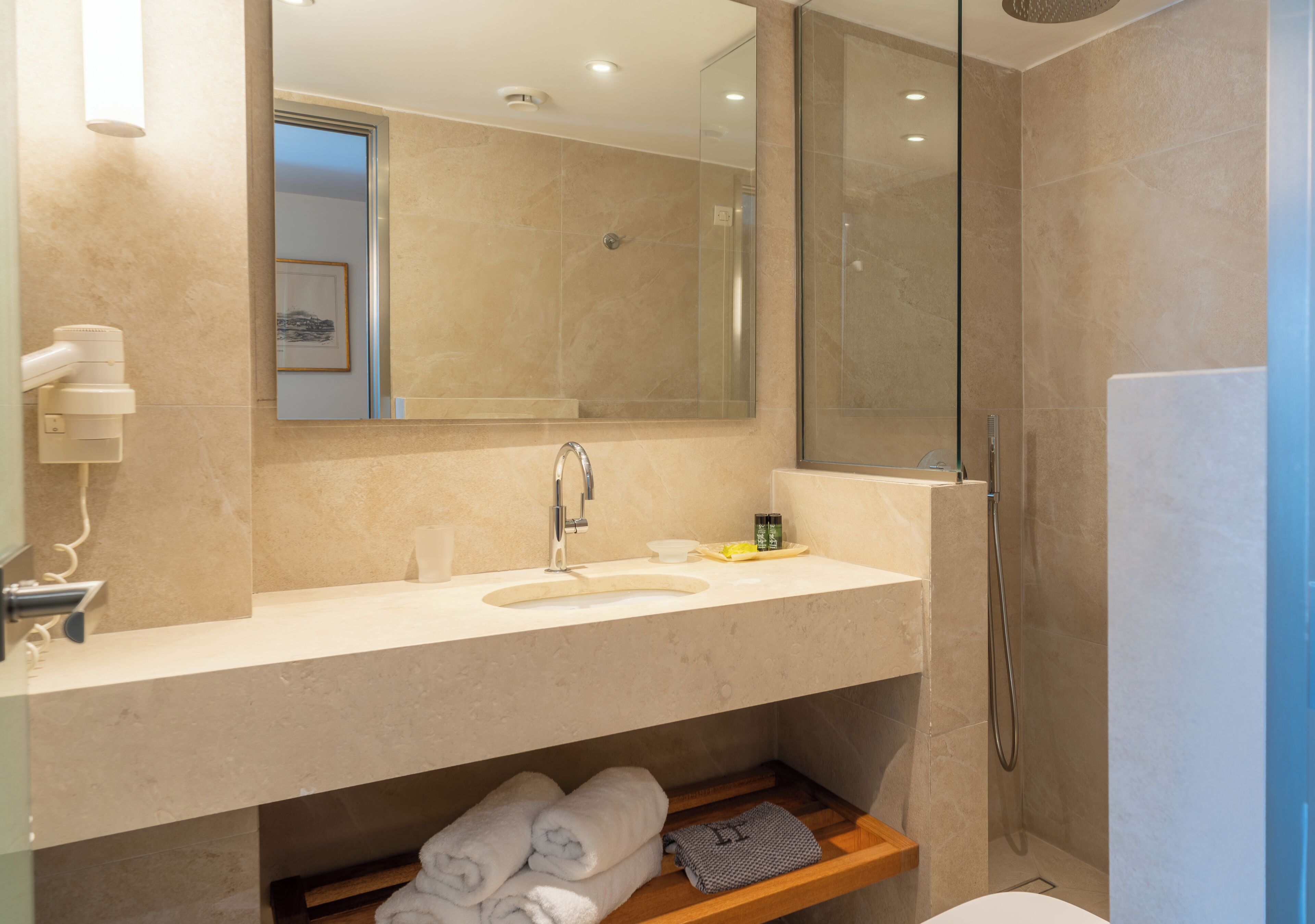 A modern bathroom with a large mirror, a sink, and a shower area.