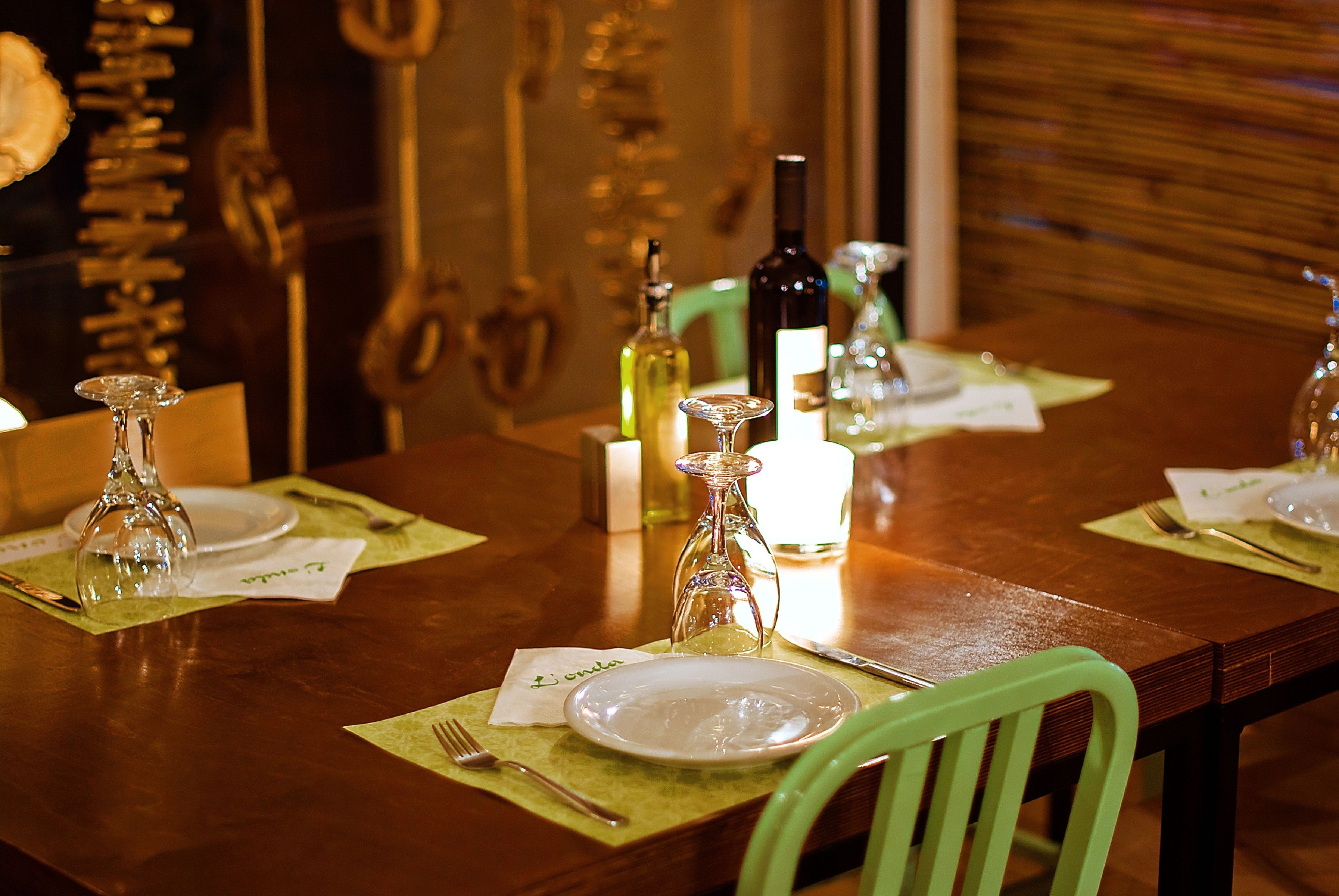 A dining table set with plates, cutlery, and a wine bottle, with a green chair visible.