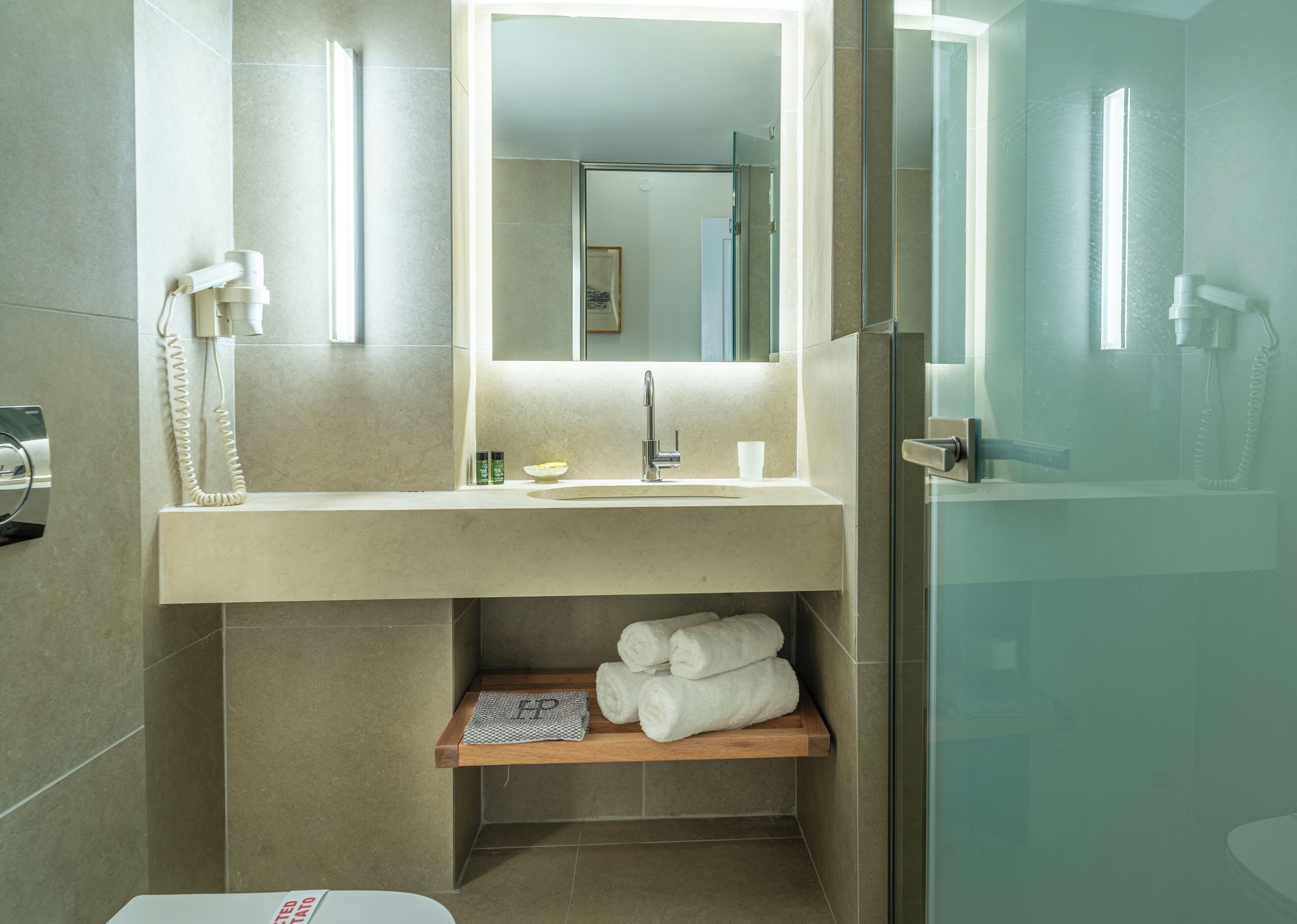 A modern bathroom with a glass shower enclosure, a sink with a towel rack, and a mirror above the sink.