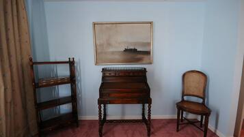 Una habitación con un escritorio de madera, una silla y un cuadro en la pared.