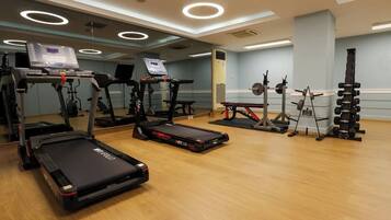 Un gimnasio con cintas de correr, elípticas y equipo de levantamiento de pesas.