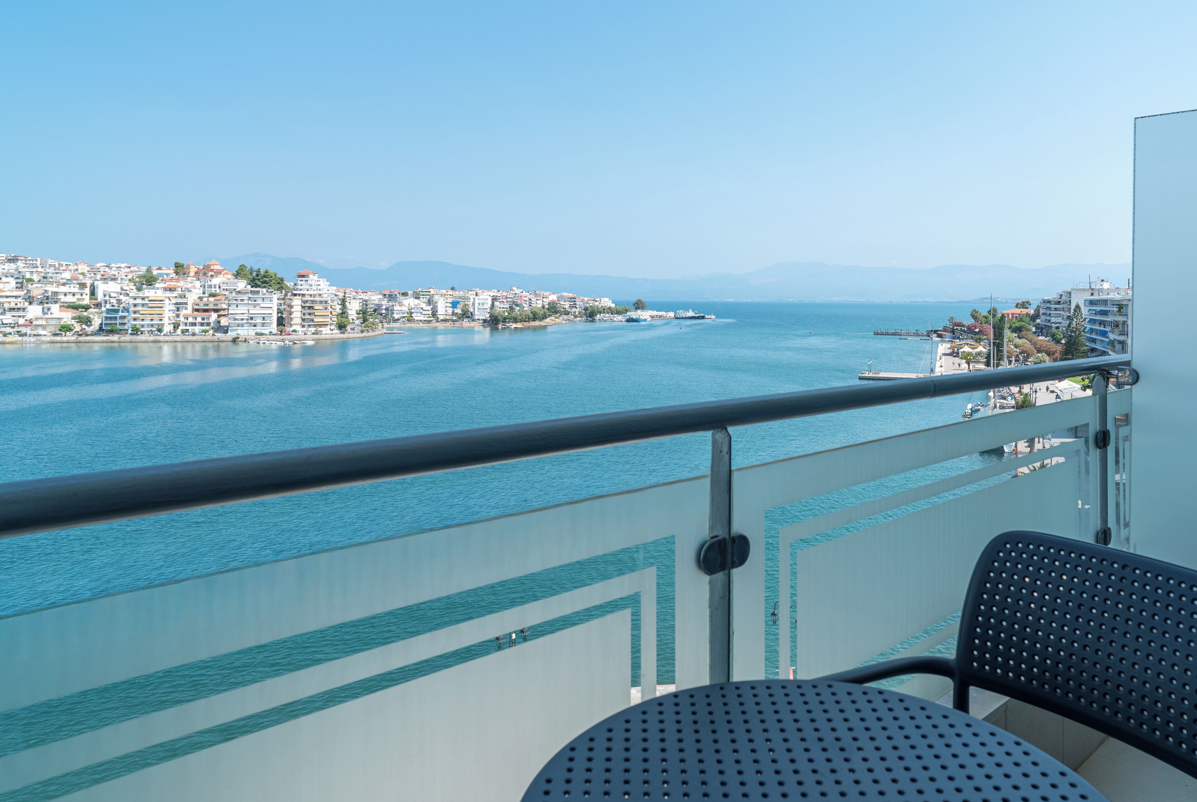 Ein Balkon mit Blick auf eine Küstenstadt, darunter Gebäude und ein Gewässer.