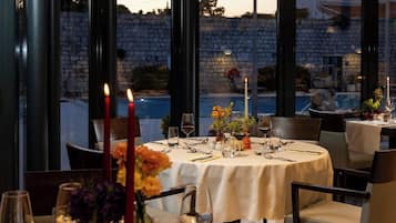 A dining table set with candles, wine glasses, and a vase of flowers.