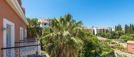 A residential area with a balcony, palm trees, and a clear blue sky.