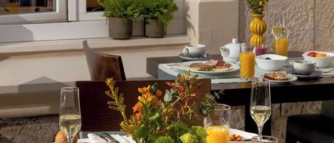 A breakfast setting with a variety of dishes, drinks, and a vase of flowers on a table.