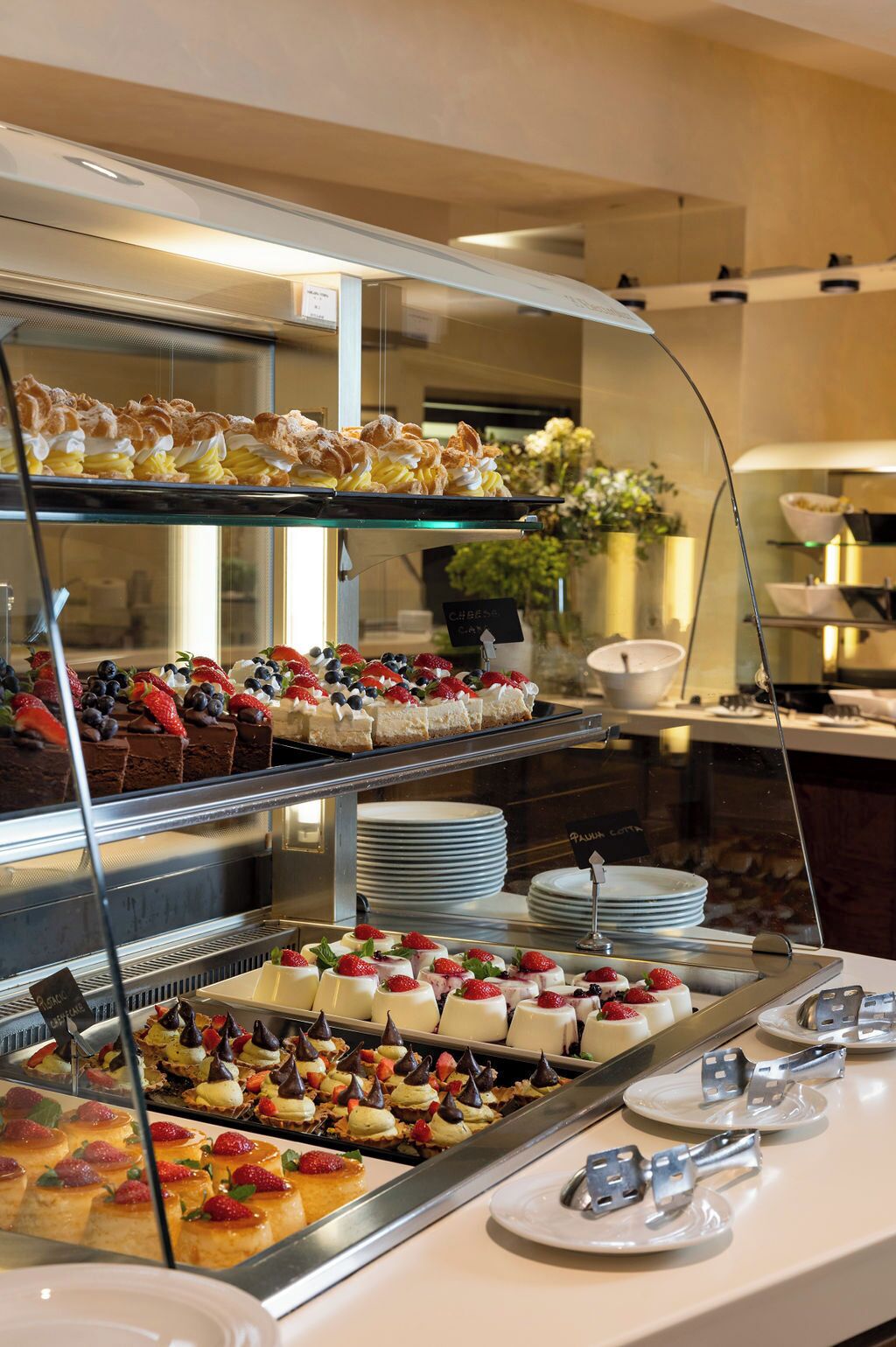 Un buffet proposant une variété de desserts, notamment des gâteaux et des pâtisseries, présentés sur des étagères en verre.