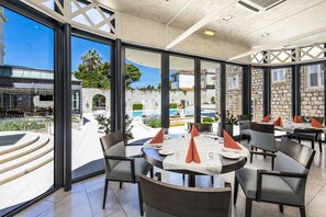 Enjoy meals with a view of the pool and surrounding greenery from this dining area.