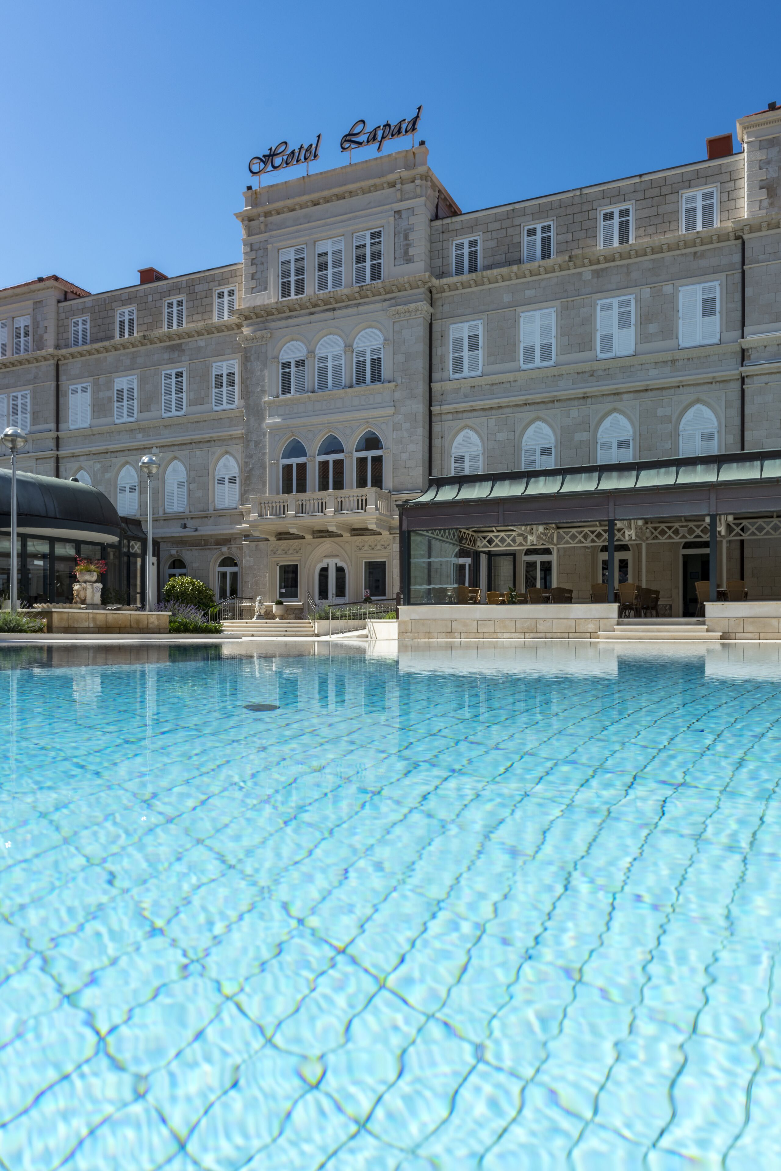 Un grand bâtiment d’hôtel avec une piscine devant.