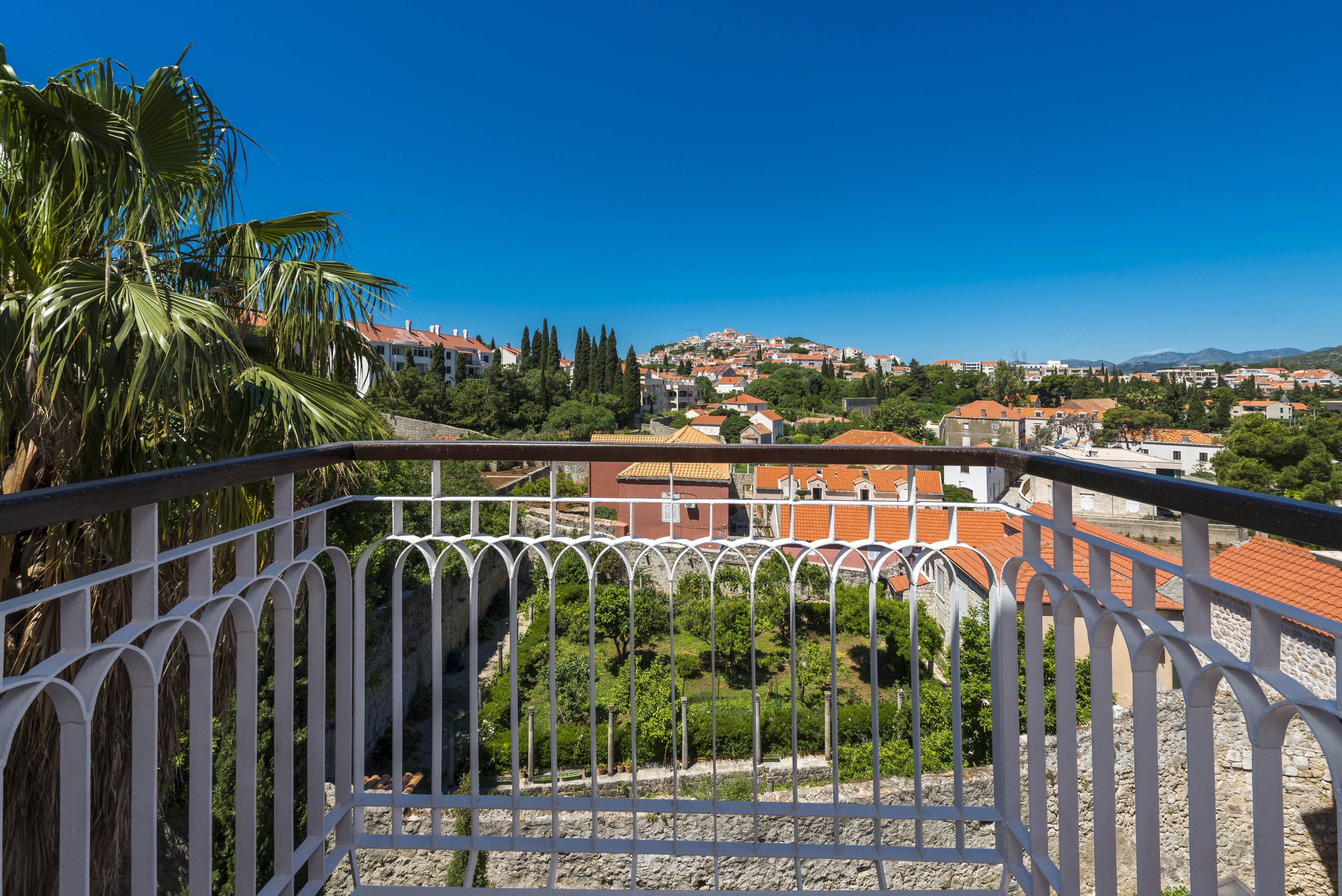 Un balcón con vista a un pueblo, con edificios y zonas verdes.