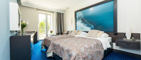 Una habitación de hotel moderna con una cama grande, un escritorio y vistas a zonas verdes por la ventana.