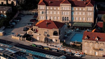Une ville côtière dotée d’un port de plaisance, de bâtiments en pierre aux toits rouges et d’un grand bâtiment aux fenêtres en arc de cercle.