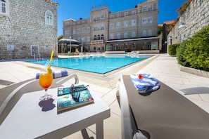 Relax by the serene pool surrounded by lounge chairs and sunbeds, with a book and cocktail glass at your fingertips.