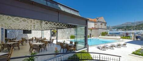 Un hotel con comedor al aire libre y zona de piscina.