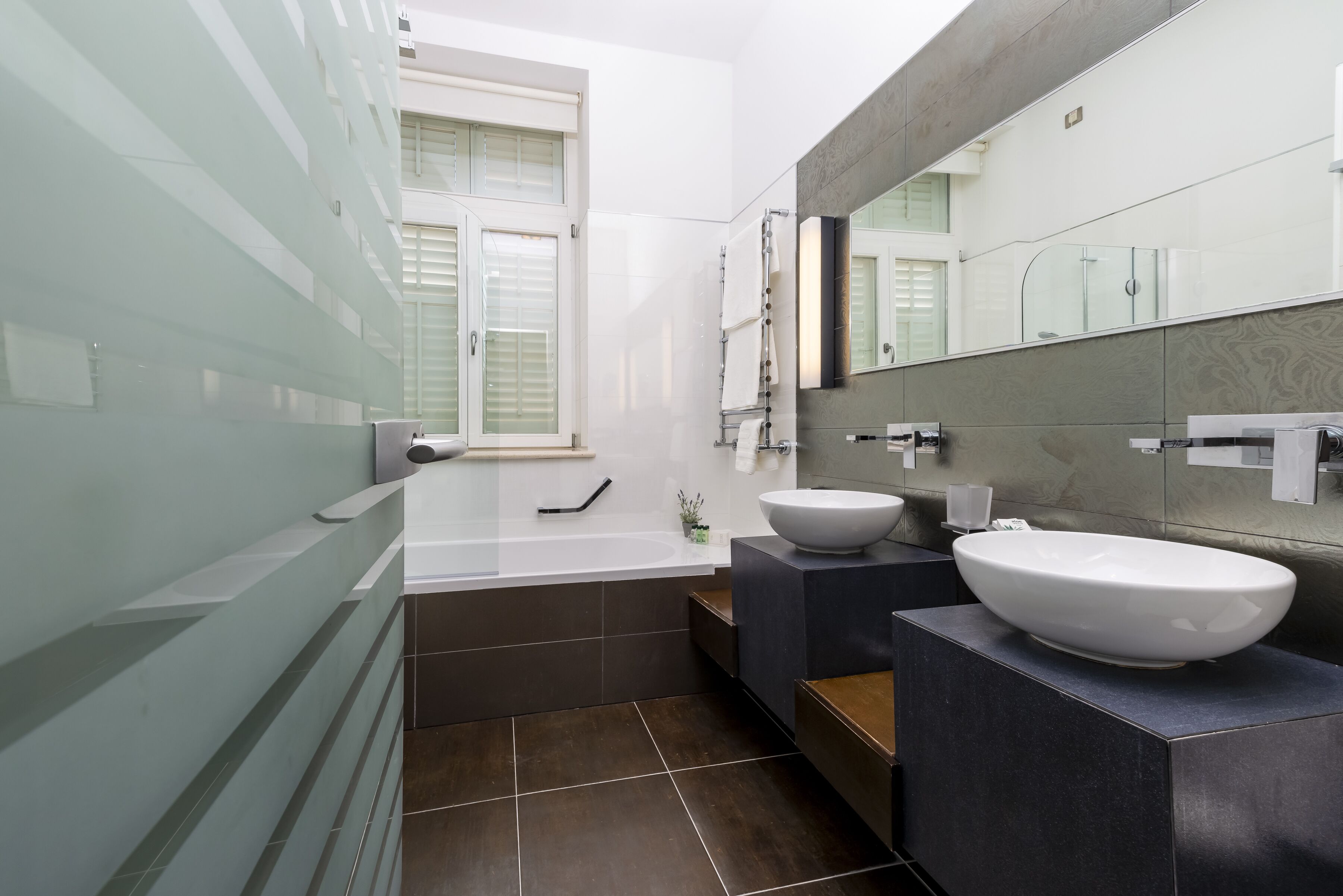Une salle de bain moderne avec une baignoire, deux lavabos et un grand miroir.