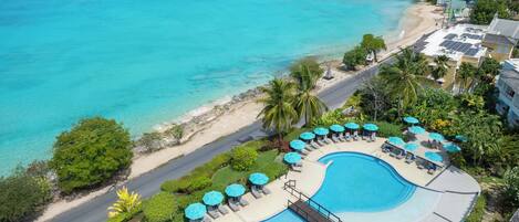 A resort with a large pool, beach access, and lush greenery.
