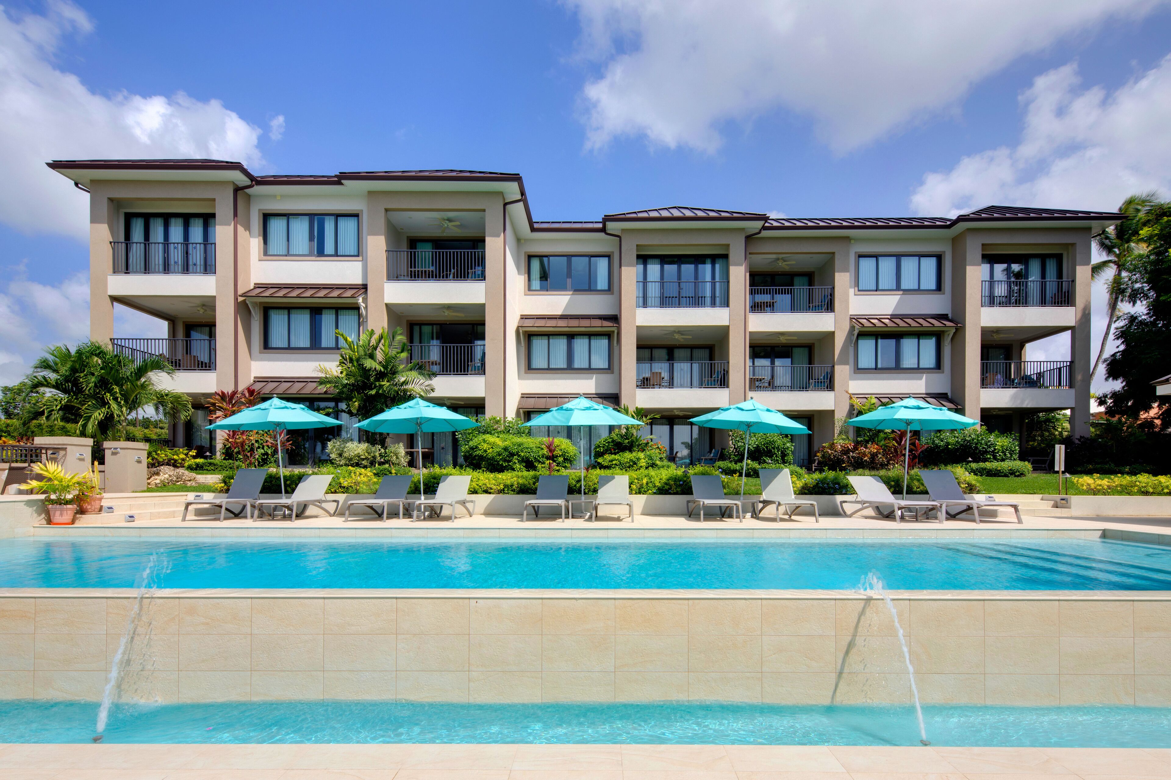 Un hôtel doté d’une piscine, de nombreux balcons et d’un espace extérieur aménagé avec des parasols.