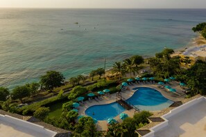 A resort with a pool, lounge chairs, and a view of the ocean.