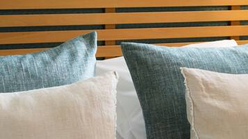 Een bed met houten latten en kussens in blauw- en wit tinten.