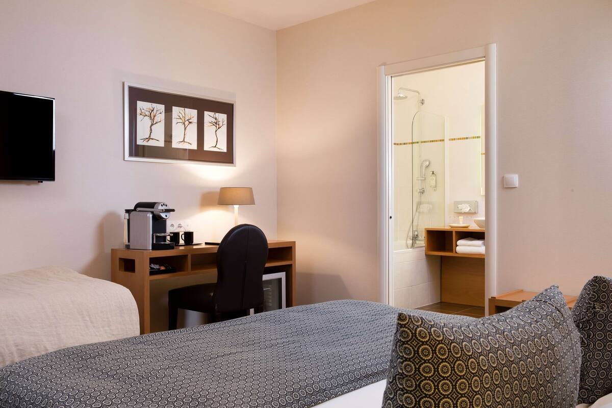Een hotelkamer met een bed, een bureau met stoel, een televisie en een douche.
