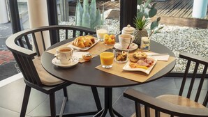 Een ontbijttafel met croissants, koffie, fruit en een fles Nature melk.