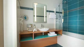 A bathroom with a white sink, mirror, and a shower area with blue tiles.