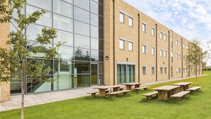 A modern building with large windows, outdoor seating, and a well-maintained lawn. - Days Inn by Wyndham Wetherby (Wetherby)
