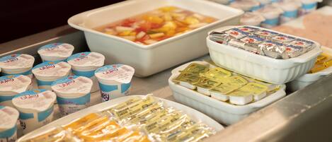 Exhibición de diversos alimentos, incluyendo yogur, queso y una ensalada de frutas.