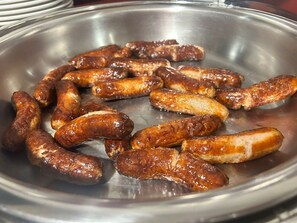 A stainless steel plate with cooked sausages.