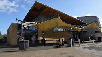 Un edificio con toldo amarillo, un letrero de Greggs y un letrero de Moto.