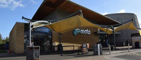 A building with a yellow awning, a sign for Greggs, and a Moto sign.