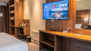 A hotel room with a bed, a desk with a flat-screen TV, wooden shelving, and a mirror. - Days Inn by Wyndham Wetherby (Wetherby)