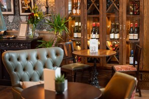 A bar area with wooden cabinets, a round table, and a tufted leather chair. - Riverside Hotel Branston by Chef and Brewer Collection (Burton on Trent)