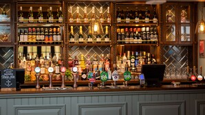 Eine Bar mit mehreren Regalen voller Flaschen, einer Kasse und einer Zapfanlage.