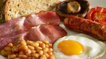Un plato con huevos, frijoles, tocino, salchichas, champiñones y tostadas.