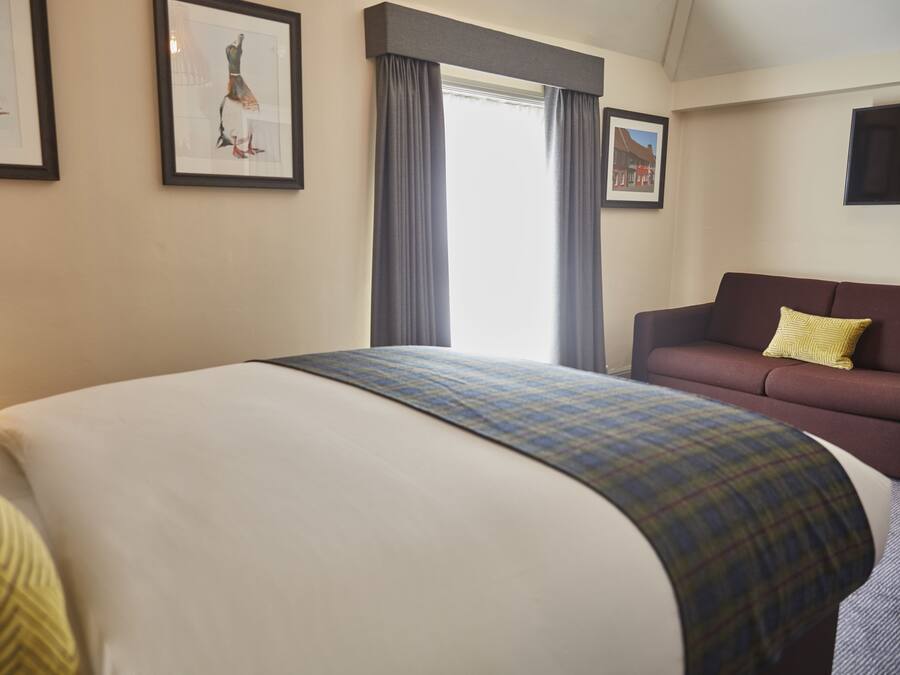 Una habitación de hotel con una cama grande, un sofá y dos cuadros en la pared.