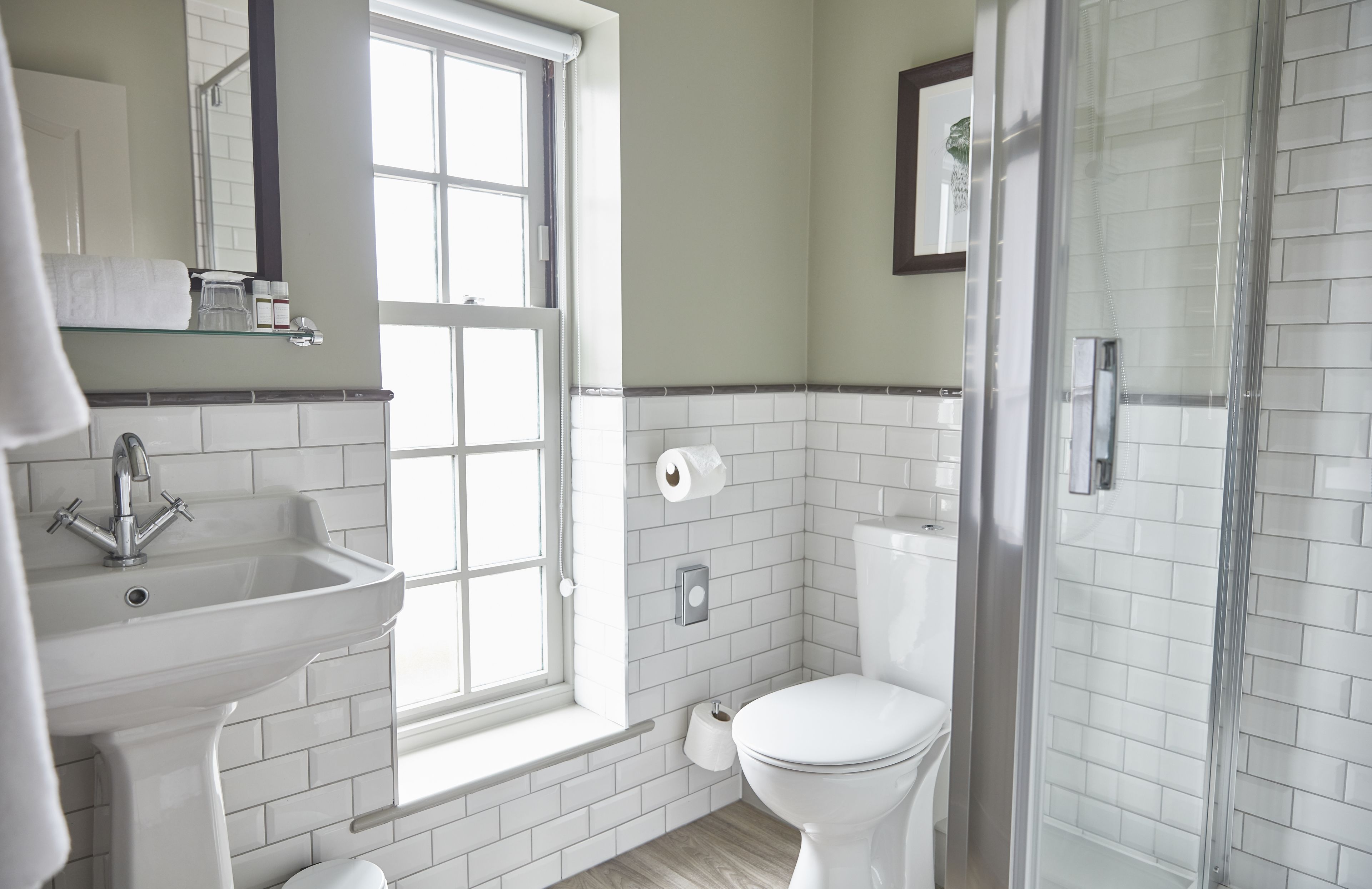 Un bagno moderno con lavandino, water e box doccia in vetro.