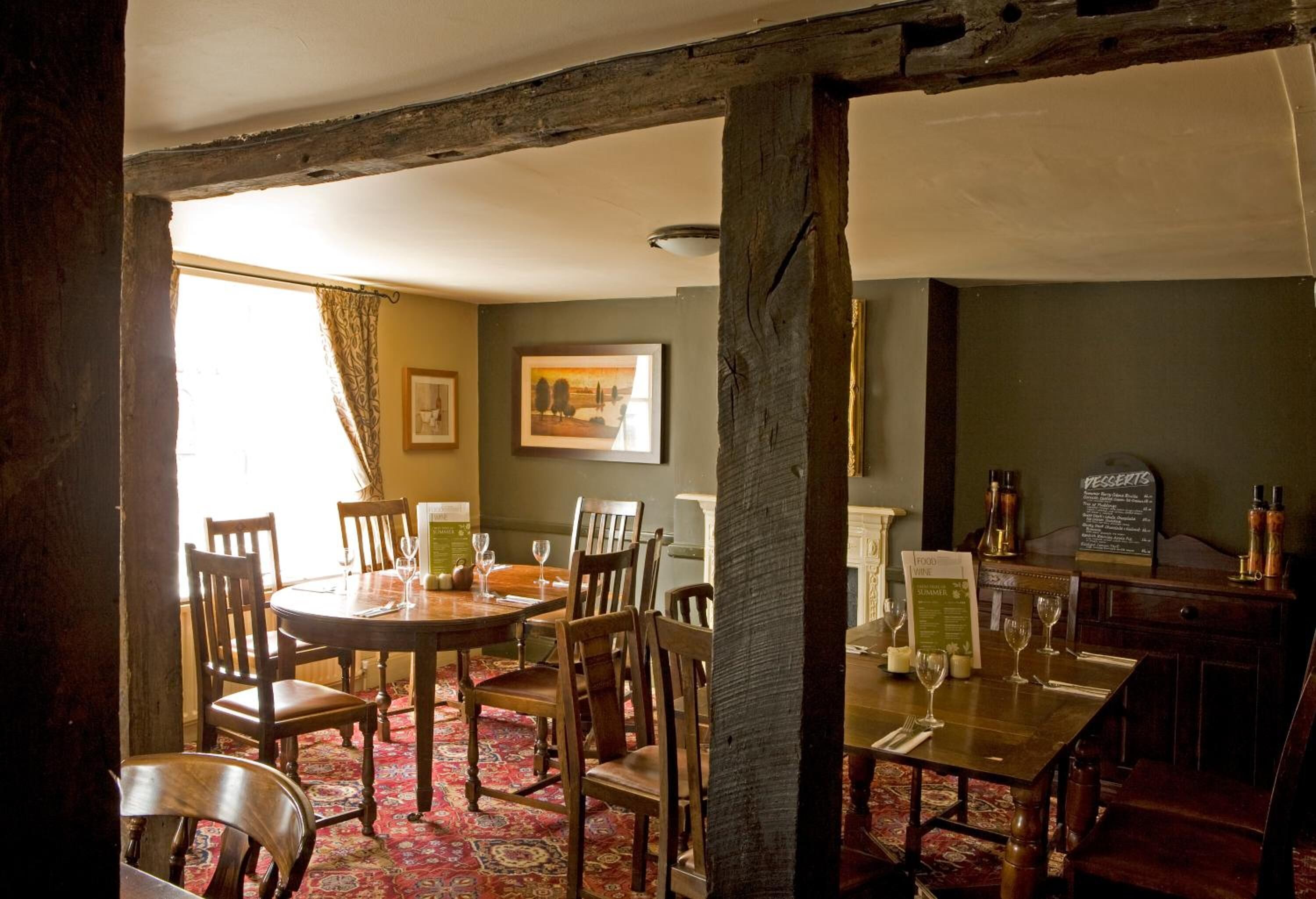 A dining area with a round table and chairs, a menu board, and a view of the outdoors.