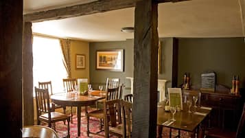 A dining area with a round table and chairs, a menu board, and a view of the outdoors.