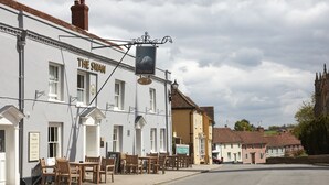 A white building with a sign reading "The Swan" and outdoor seating. - Swan Hotel Thaxted by Greene King Inns (Dunmow)