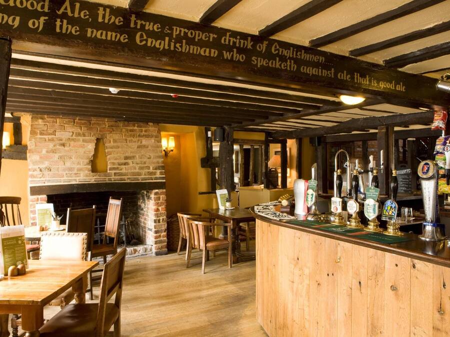 Un interior de pub con barra de madera, paredes de ladrillo y chimenea.