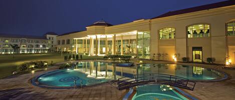 Een buitenzwembad, parasols bij het zwembad en ligstoelen