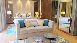 Una habitación de hotel con cama, sofá, dos mesitas y un espejo grande.