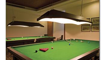 A pool table with balls, overhead lighting, and framed artwork on the wall.