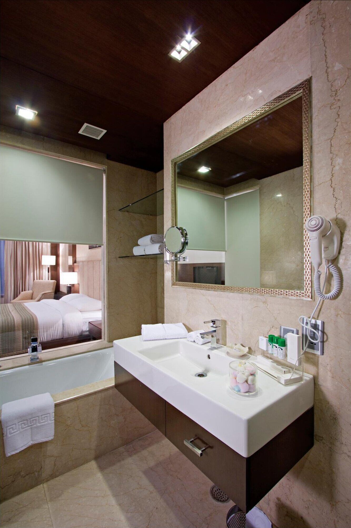 A modern bathroom with a large mirror, a bathtub, and a vanity with toiletries.
