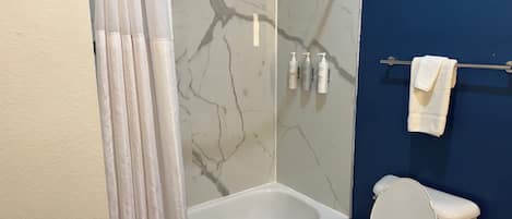 Une salle de bain avec une baignoire, des toilettes et un rideau de douche.