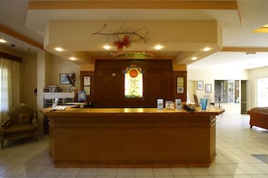 A reception area with a wooden counter, a decorative stained glass window, and a chandelier.