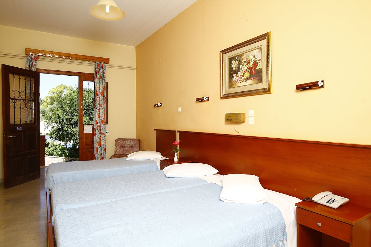 Quarto de hotel com duas camas, cabeceira de madeira, mesa de cabeceira com telefone e quadro na parede.