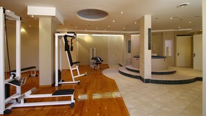 Une salle de sport spacieuse, dotée de divers appareils d’exercice, d’un plancher en bois et d’un design de plafond moderne.