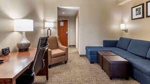 Une chambre d’hôtel équipée d’un bureau, d’une chaise, d’un canapé et d’un pouf.