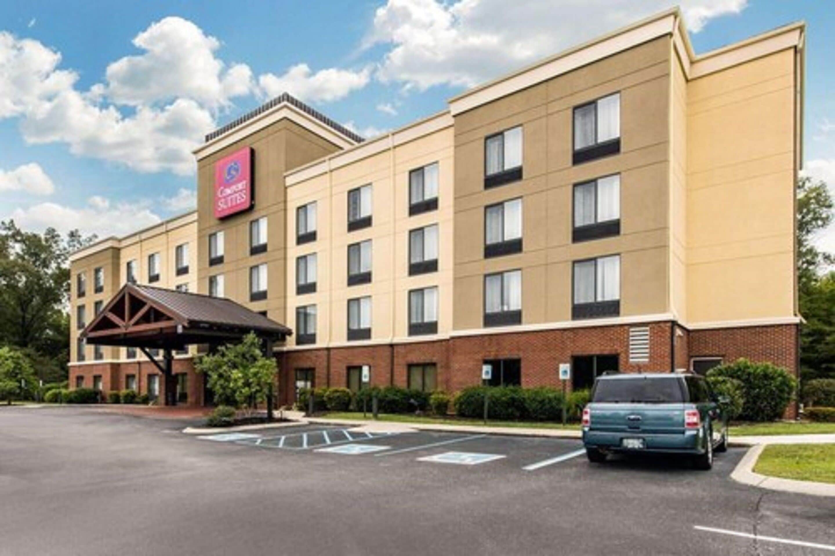 A hotel with a prominent sign, multiple floors, and a parking lot.